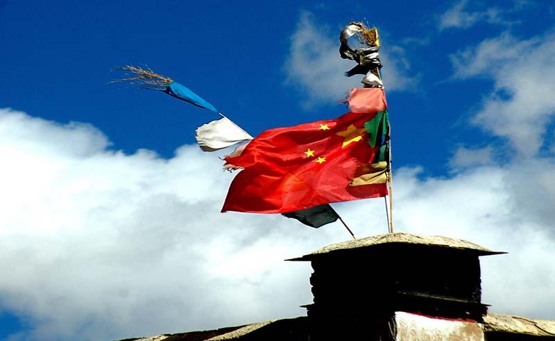 (雅鲁藏布江畔藏寨上的国旗和经幡共舞)